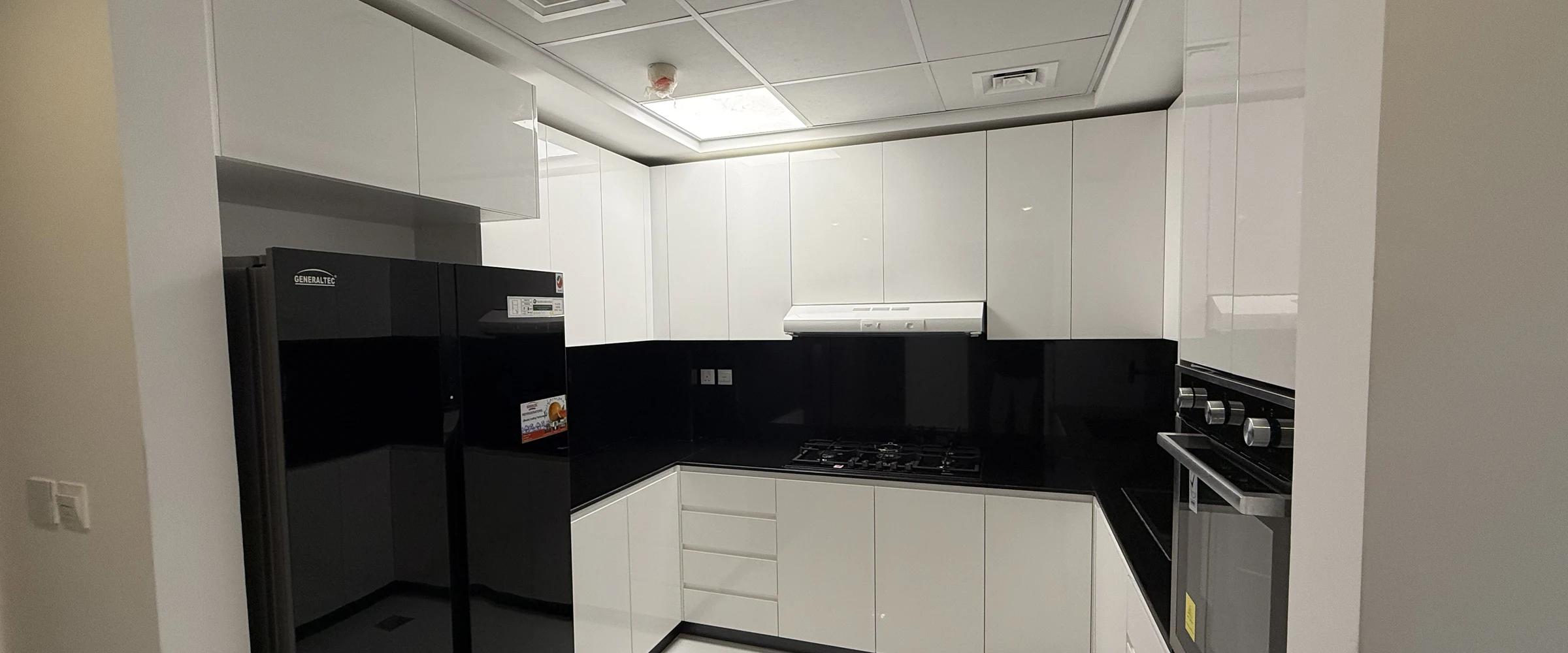 A fitted kitchen by Miles Woodworks, with gloss white units and a black worktop